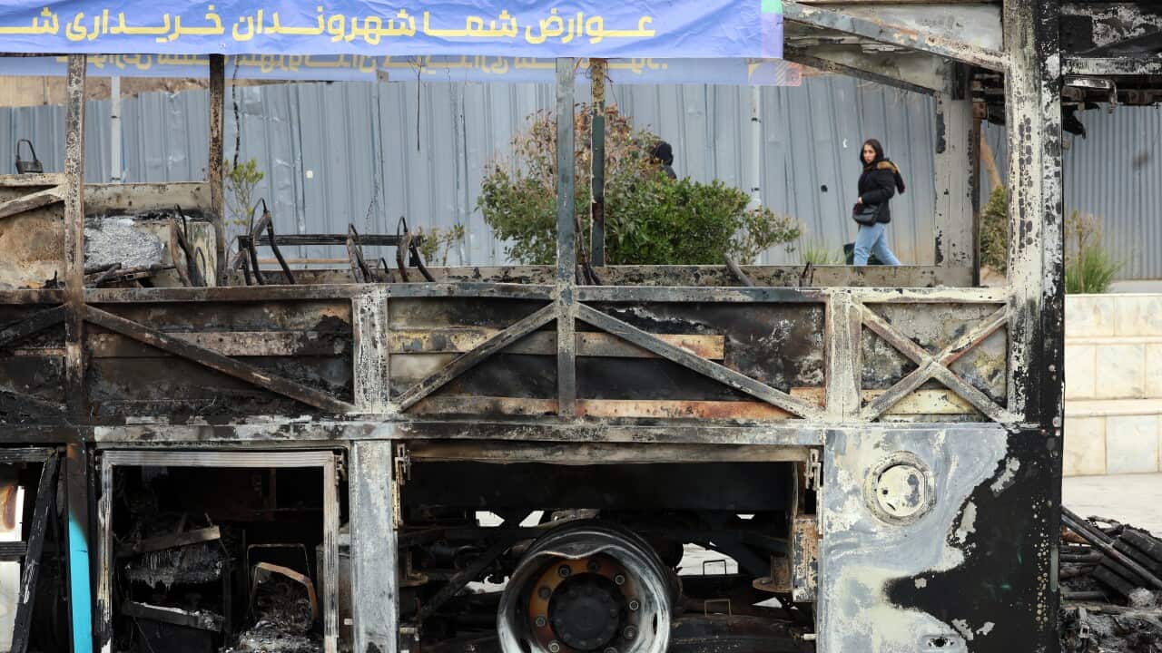 Iranians pass wreckage of public bus in Tehran amid wave of anti-government protests