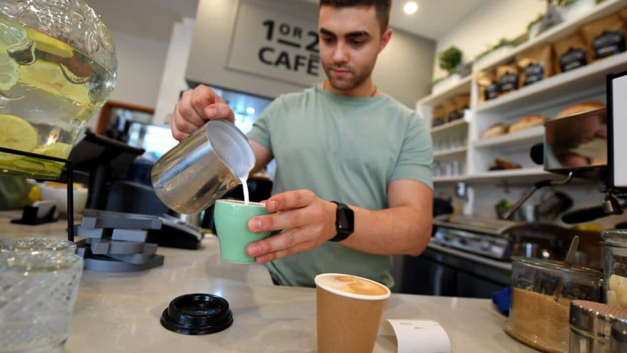A barista working at a coffee machine at a cafe in Canberra