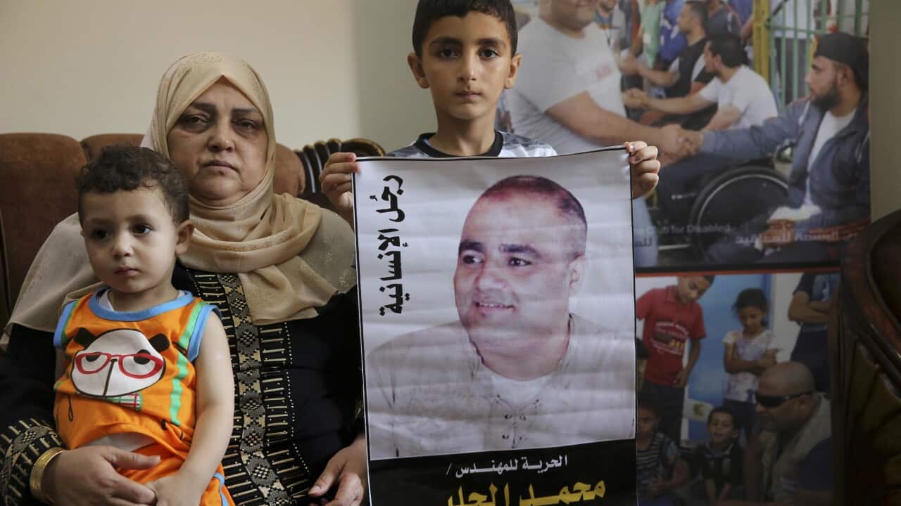 A woman and two kids hold a man's poster