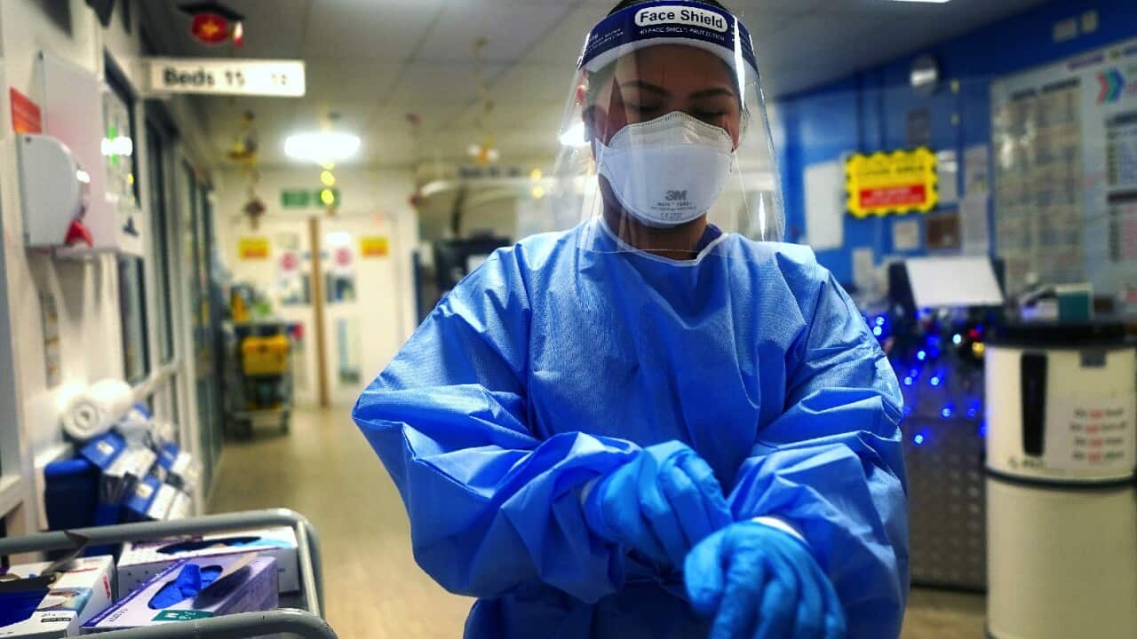 A nurse puts on full PPE on a ward for COVID-19 patients at King's College Hospital in south east London.