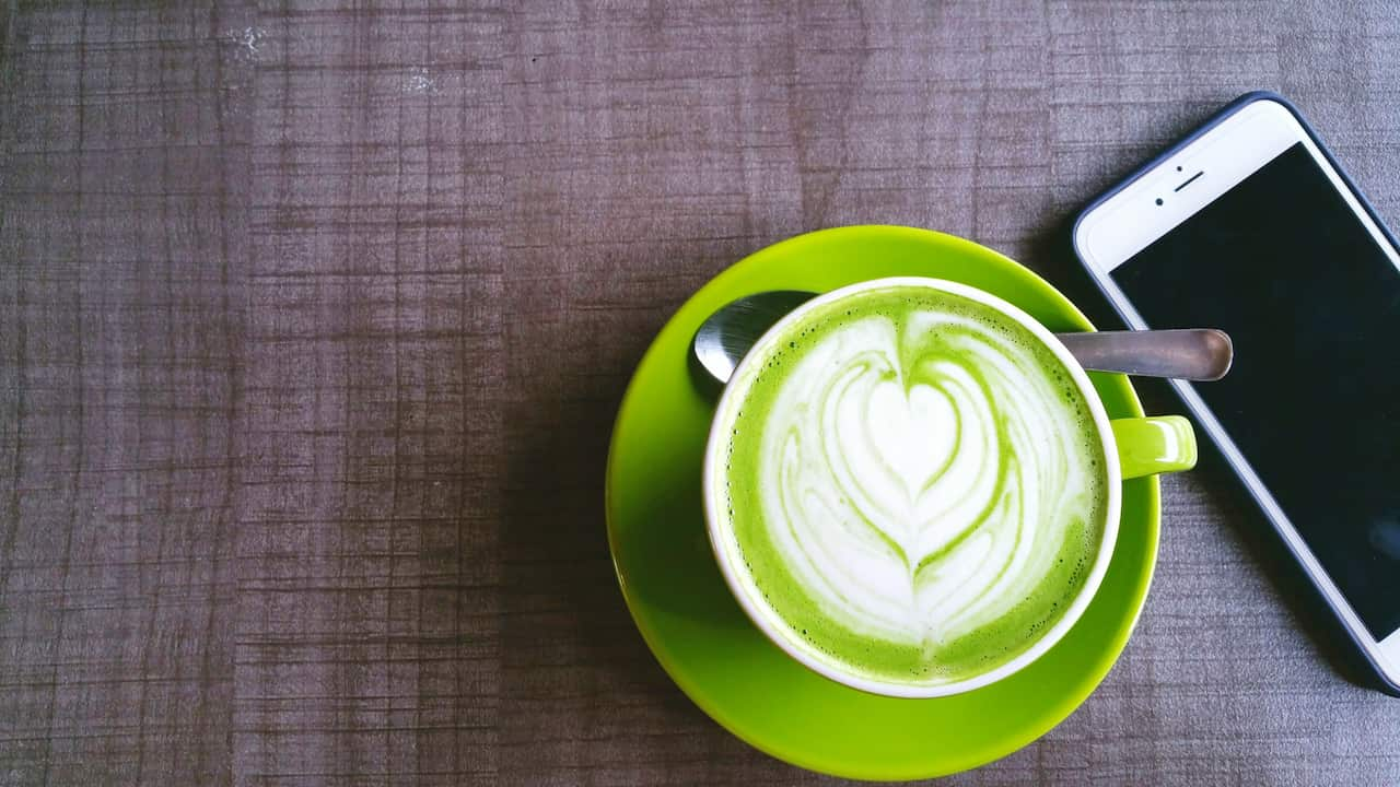 Directly Above Shot Of Matcha Latte By Mobile Phone On Table