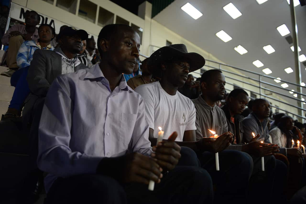 Rwandan men hold candles during a night vigil and prayer for genocide victims at the Amahoro stadium in Kigali, Rwanda (AAP)