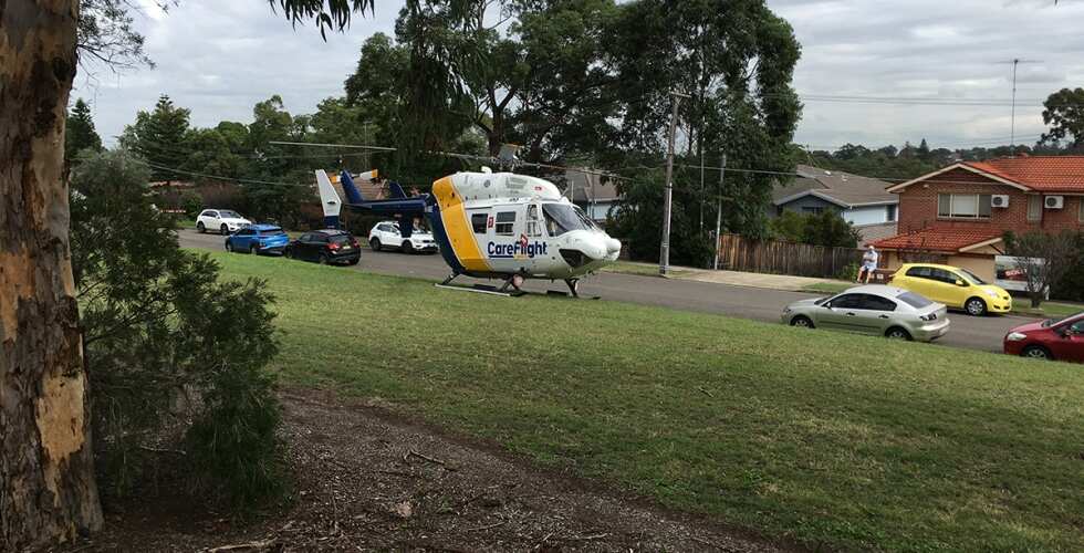 A CareFlight helicopter landed on a grass field next to the road.