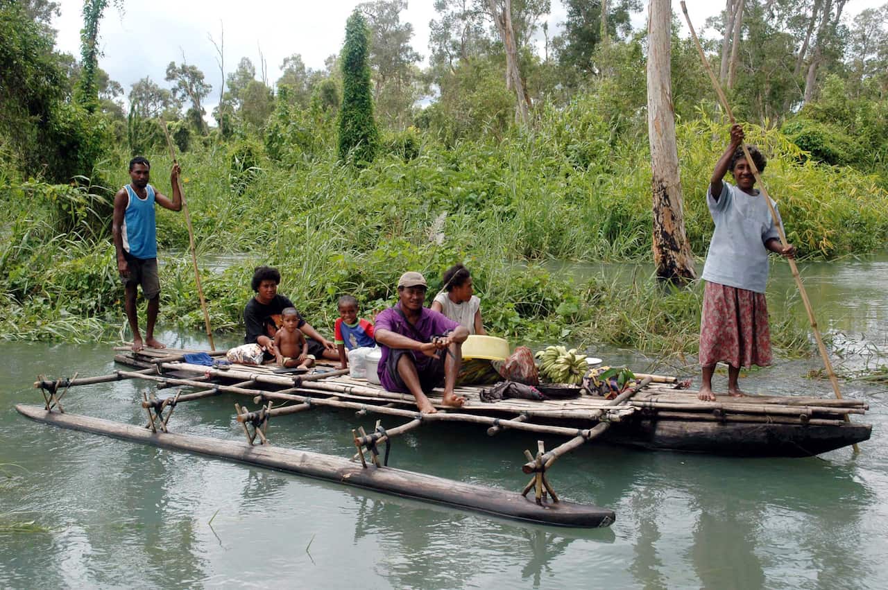 A canoe-load of people from flooded Biotou village in Papua New Guinea's Central Province make their along a waterway.