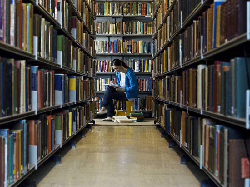 A young woman reads a book in a library