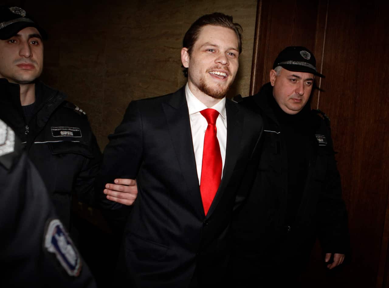 Australian citizen Paul Palfreeman, center, smiles at a journalist as he is escorted by Bulgarian policemen after his trial.