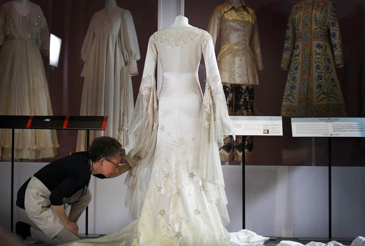 Senior conservator from the Victoria and Albert Museum of London, Frances Hartog, inspects an embroidered silk satin wedding dress during the installation of "200 Years of Wedding Fashion from the Victoria and Albert Museum, London"