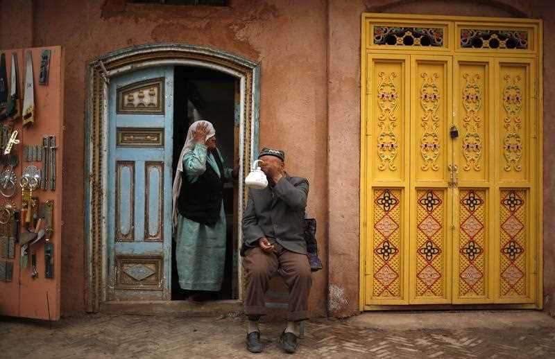 A man of the Uighur ethnic group has tea while his wife looks on in the old town of Kashgar, Xinjiang Uighur Autonomous Region, China, 24 May 2013.