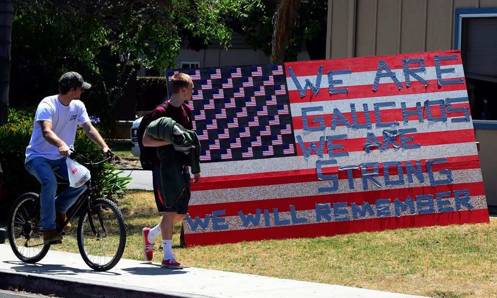 Two students look at a sign that reads 'We are Gauchos We are Strong We will Remember' set up outside an apartment in the college town of Isla Vista, California, USA, 25 May 2014 where a deadly shooting rampage left seven dead and 13 wounded. (AAP)