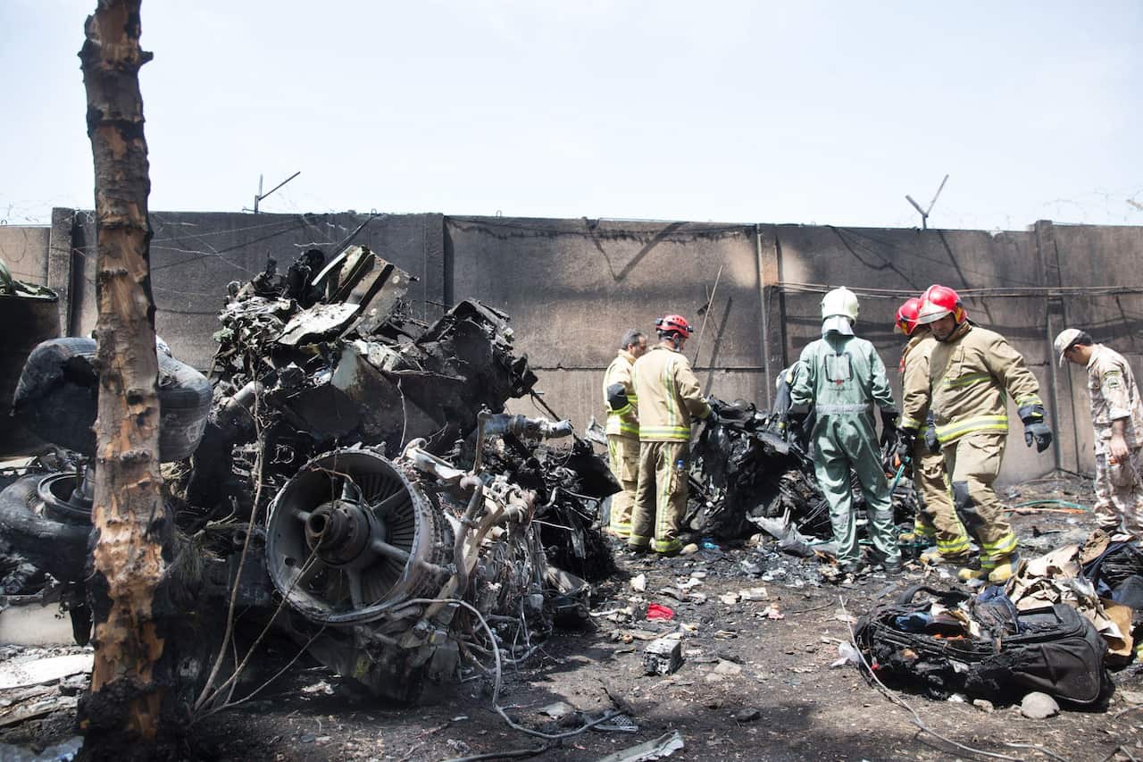 Iranian rescue personnel inspecting the scene of a plane crash near Tehran's Mehrabad airport