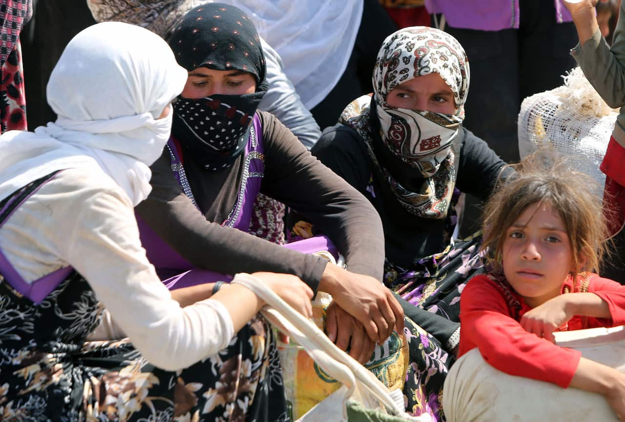 Displaced Iraqi Yazidi women gather sitting at the Bajid Kandala camp near the Tigris River, in Kurdistan's western Dohuk province. (AAP)