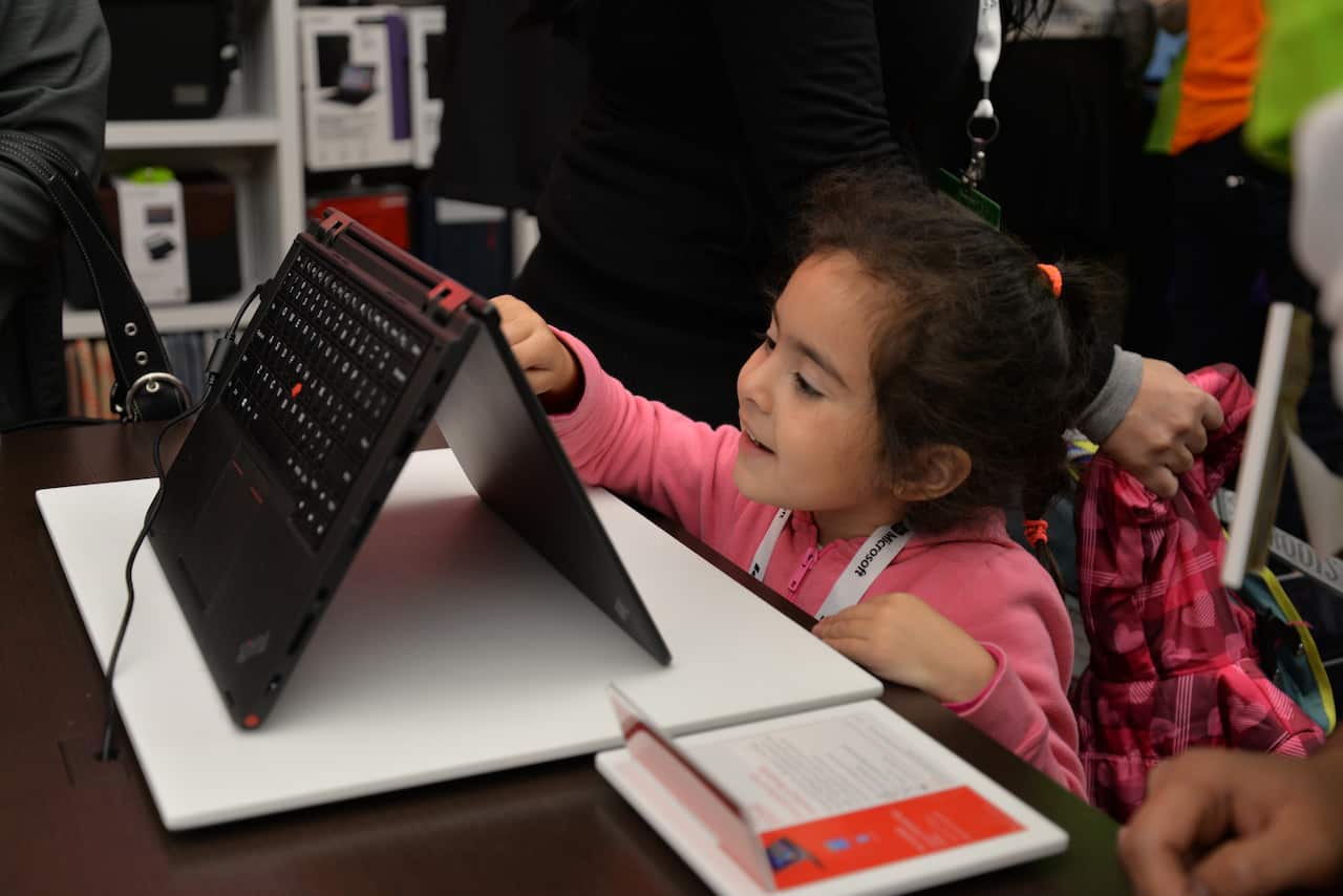A young girl examines a laptop computer (File: AAP)
