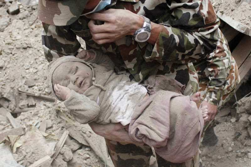 four-month-old baby boy Sonit Awal is held up by Nepalese Army soldiers after being rescued from the rubble of his house in Bhaktapur,
