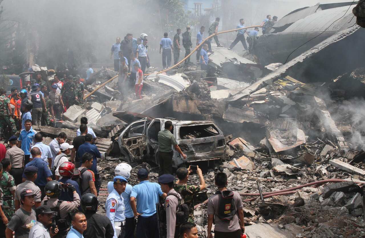 Firefighters and military personnel inspect the site where an Air Force cargo plane crashed in Medan, North Sumatra, Indonesia, June 30, 2015. (AP Photo/Gilbert Manullang)