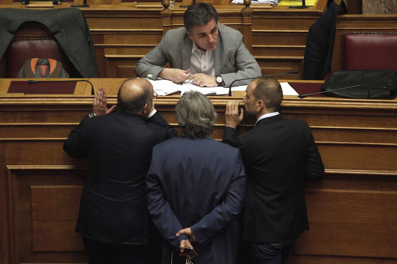 Greek Finance Minister Euclid Tsakalotos talks with lawmakers during a parliament vote