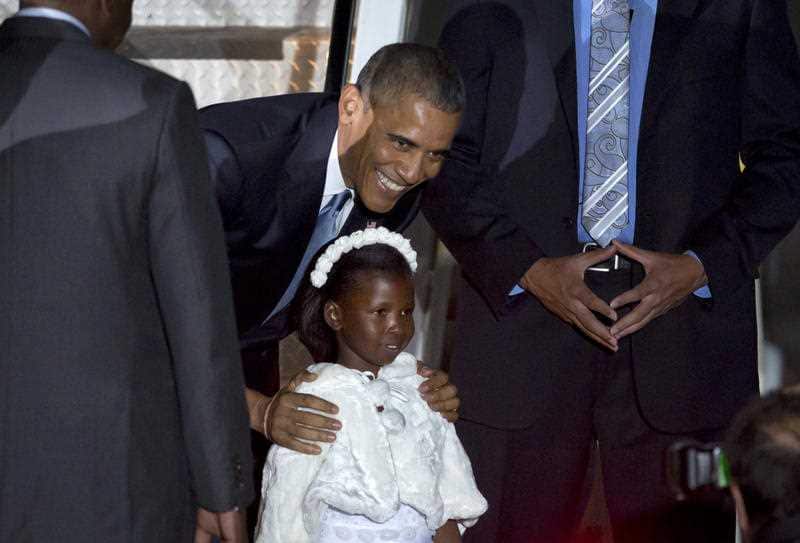 President Barack Obama poses for a photograph with Joan Wamaitha, 8, who gave him flowers on his arrival at the Jomo Kenyatta International Airport in Nairobi