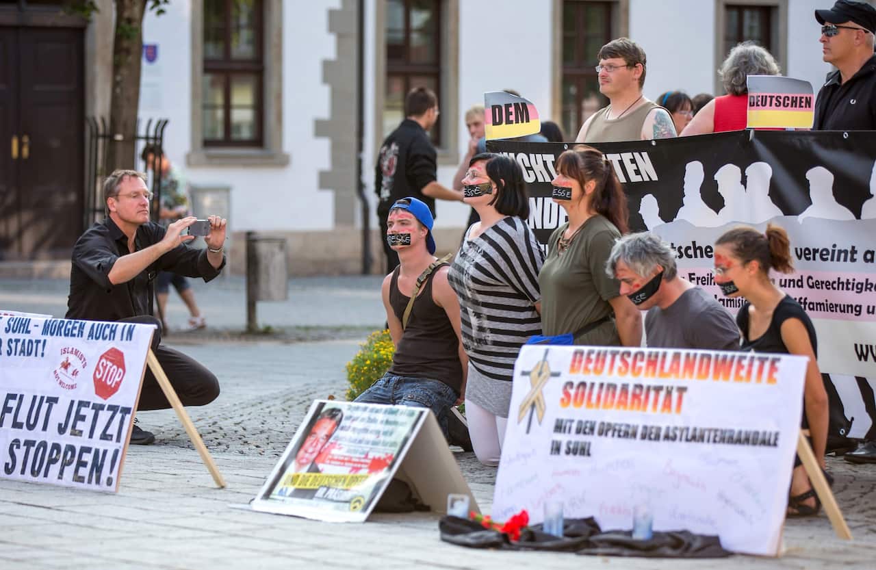 Right-wing demonstrators sit behind a placard that reads ''Germany-wide solidarity' on the market square in Suhl, Germany, 22 August 2015. EPA/MICHAEL REICHEL