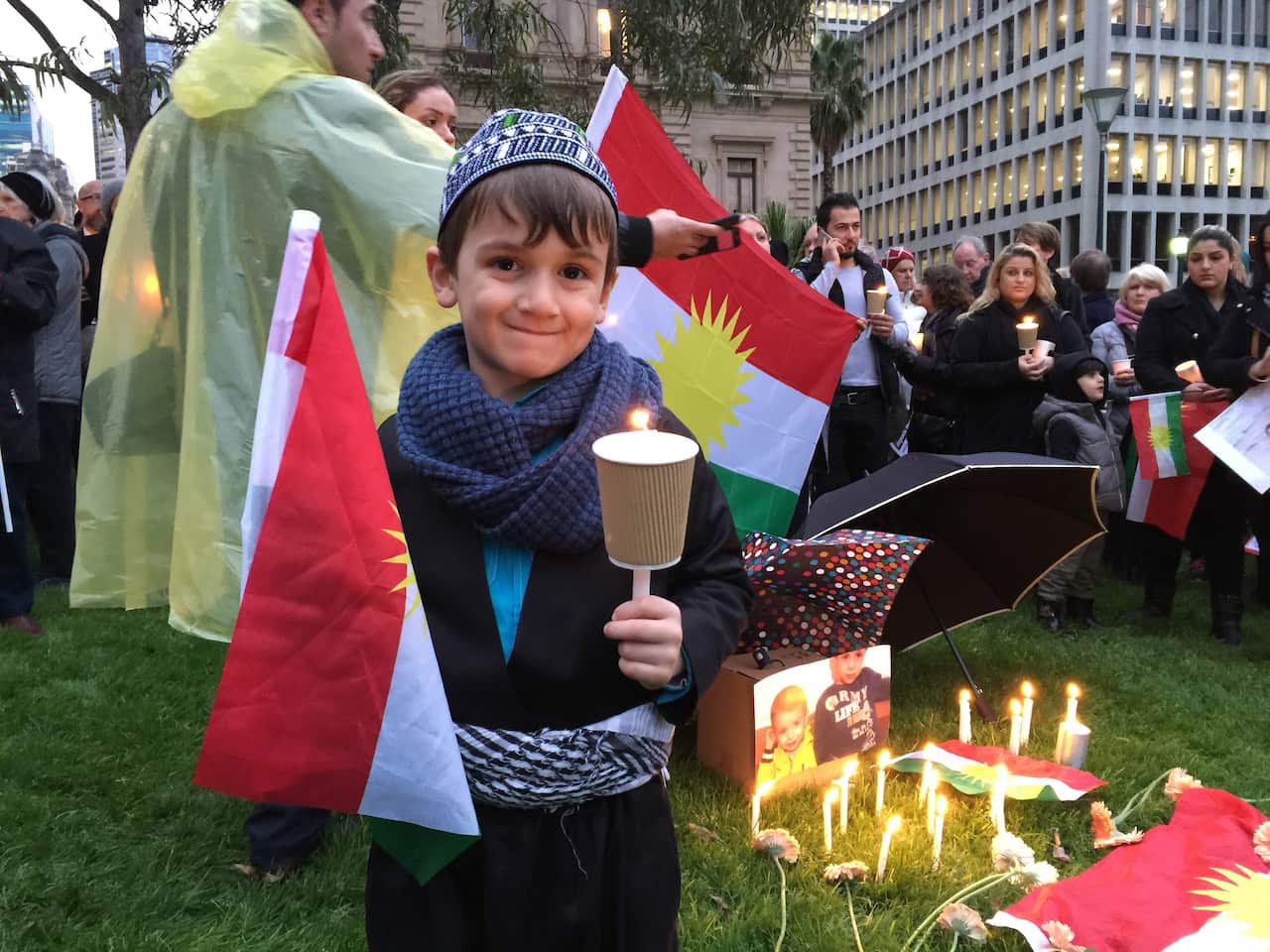 Karez Najifar, 5, dressed in traditional Kurdish dress during a refugee vigil at Melbourne's Treasury Gardens on Monday, Sept. 7, 2015. Thousands braved the wet weather to honor drowned refugee boy Aylan Kurdi. (AAP Image/Jamie Duncan) NO ARCHIVING