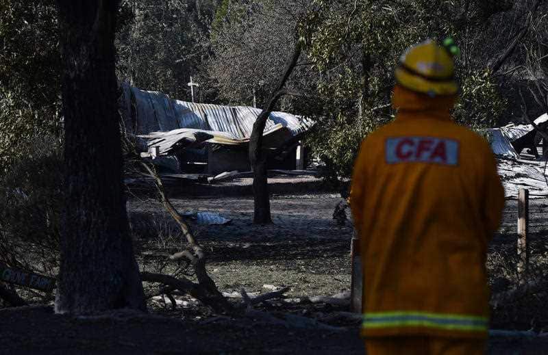 A Country Fire Authority firefighter surveys the ruins of a house near Lancefield north of Melbourne.