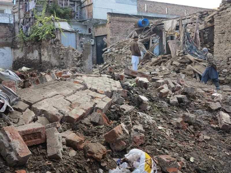 People survey a damaged house a day after a 7.5 magnitude earthquake in Swat valley, Pakistan.