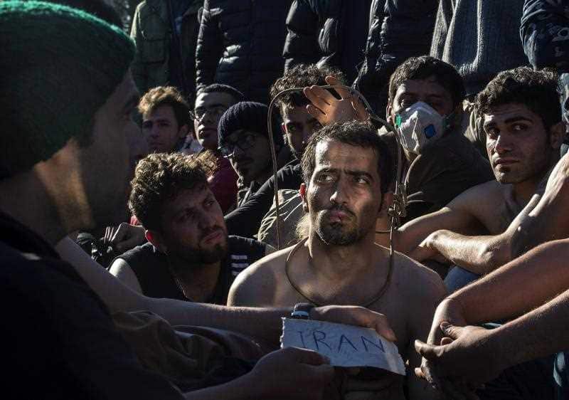 Several migrants, with stitched mouths in a sign of protest, sit in front of police cordon after they were barred from crossing the border, near Gevegelija, The Former Yugoslav Republic of Macedonia, 23 November 2015.