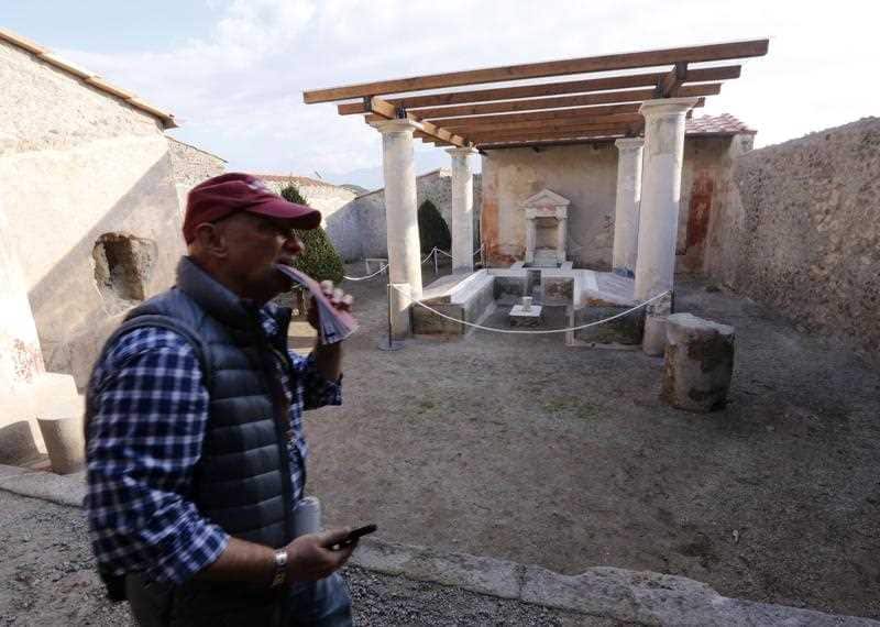 A tourist walks in the Casa dell'Efebo, one of the six domus reopened to the public in the archeological venue of the ancient Roman town of Pompeii.