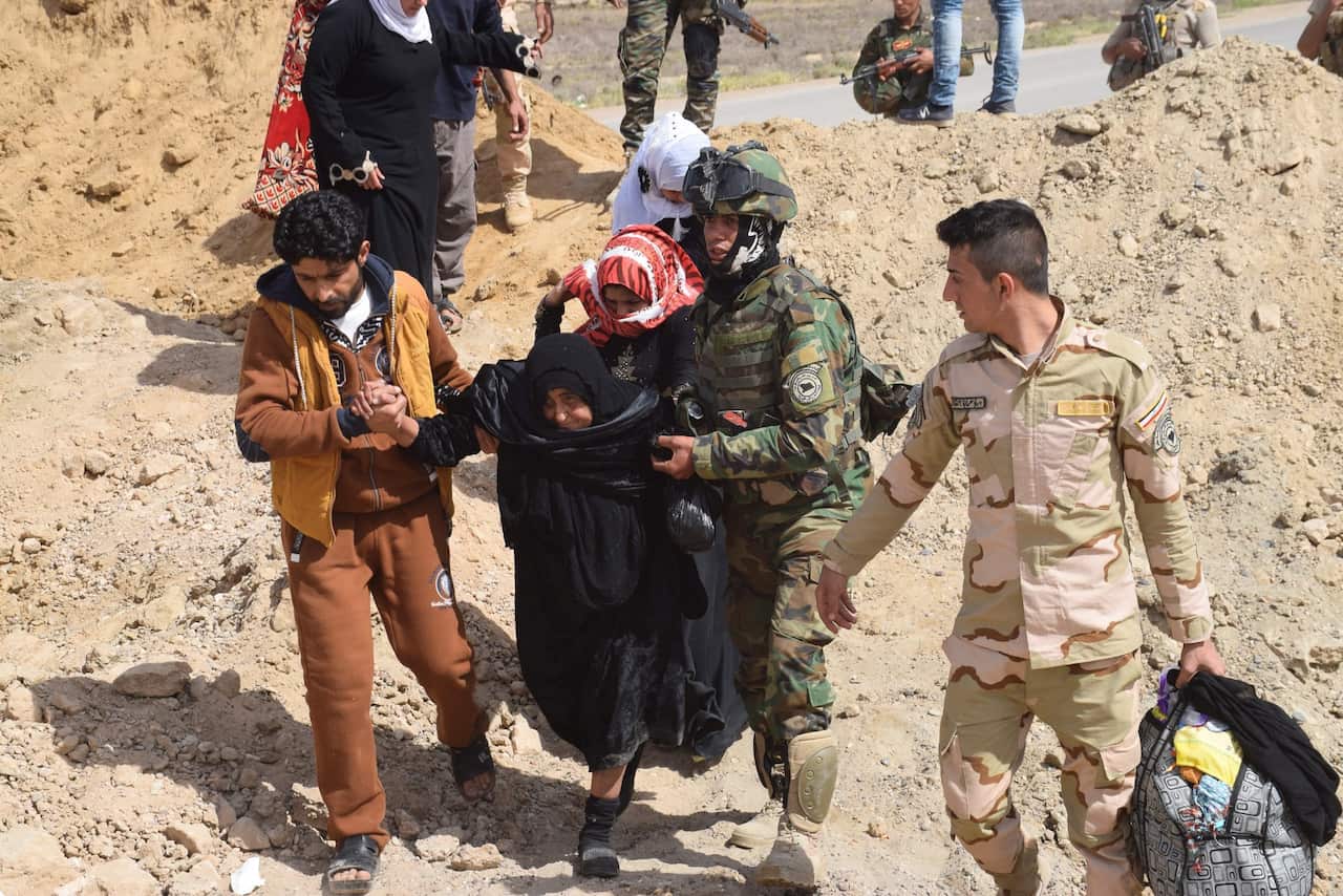 A file photo shows Iraqi soldiers helping an elderly woman while observing the evacuation of families from the recently recaptured town of Zangura, near Ramadi 