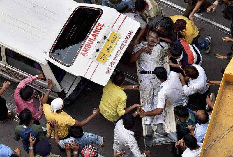 An injured traffic police officer is rushed to an ambulance after an under construction over bridge partially collapsed in Kolkata, India.