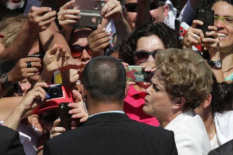 Brazilian President Dilma Rousseff, center, greets supporters as she leaves Planalto president palace in Brasilia, Brazil, Thursday, May 12, 2016. 