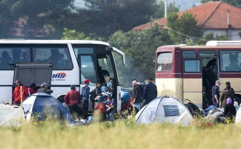Refugees put their belongings in the buses during a police operation at the makeshift refugee camp near the Greek-Macedonian border town of Idomeni