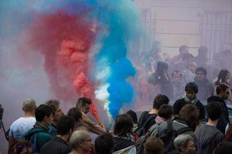 Protesters hold smoke bombs as clashes between demonstrators and riot policemen erupt during a protest against government's controversial labor reforms