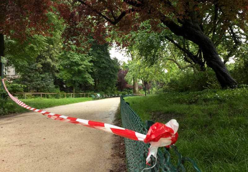 White-and-red tape is strung across a sandy pathway through Park Monceau.