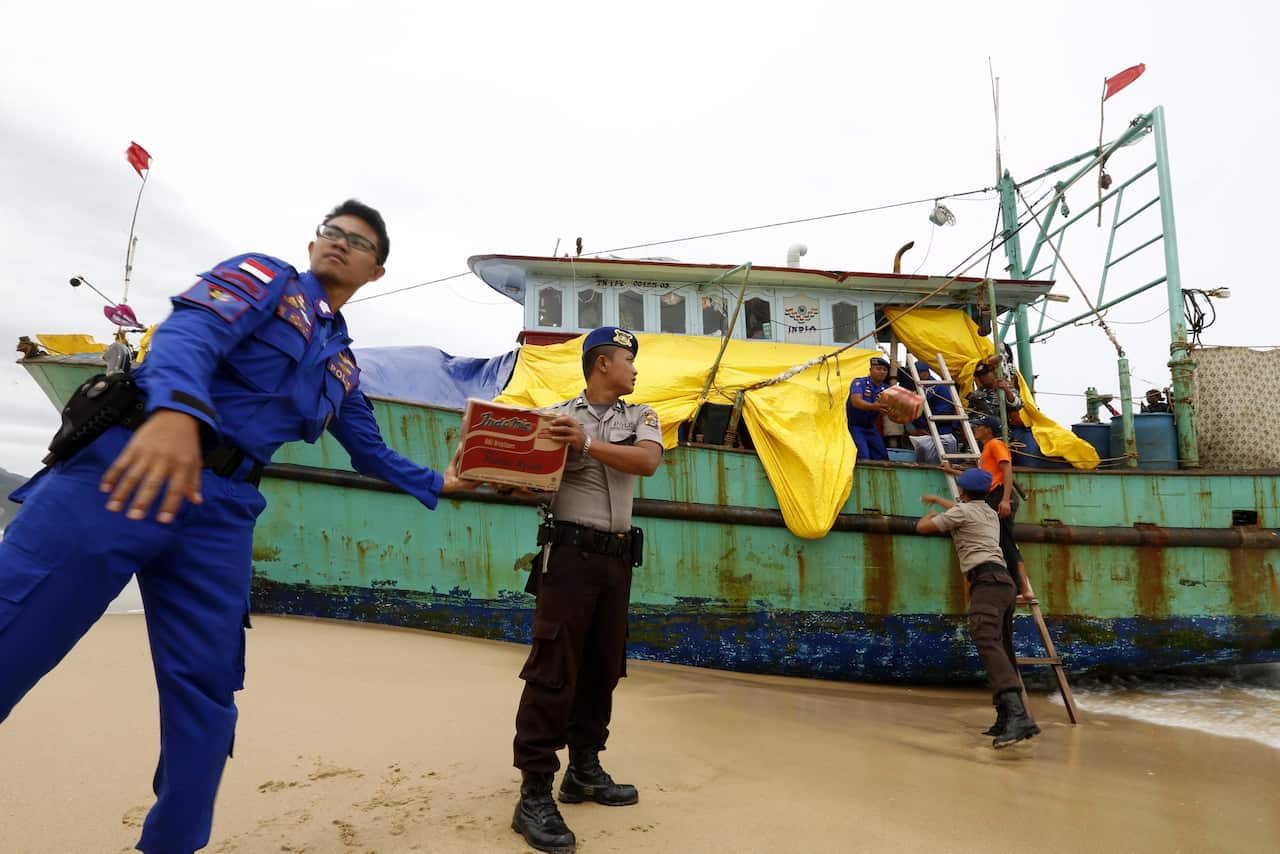 Indonesian police officers load food for Sri Lankan migrants into their boat at Lhoknga Beach, Aceh, Indonesia