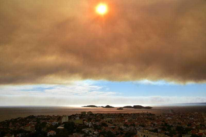 A heavy cloud of smoke is seen above Marseille coming from a fire that spread above the highway near Vitrolles.