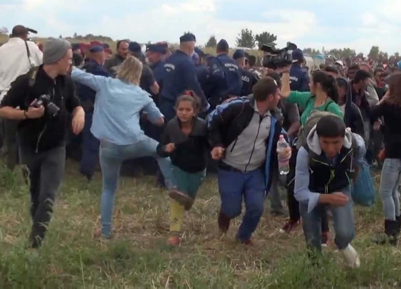 A Hungarian camerawoman, center left in blue, kicks out at a young migrant who had just crossed the border from Serbia near Roszke Hungary. Sept 2015