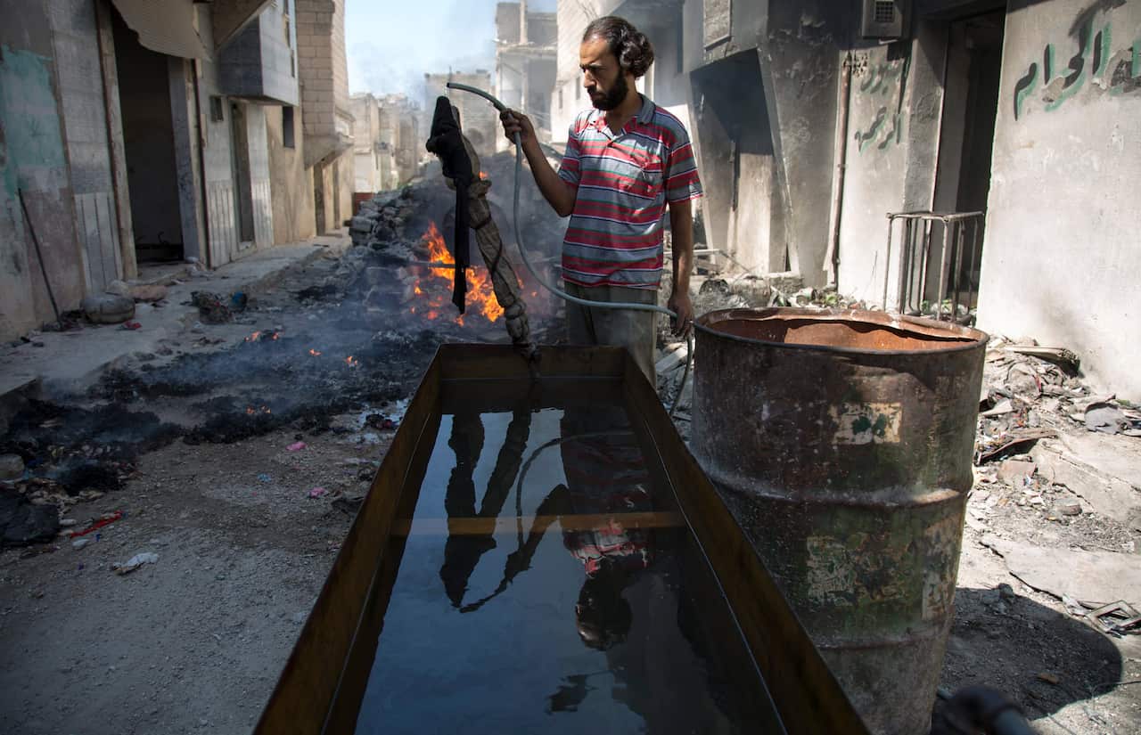 A Syrian holds a hose used for converting plastic into fuel in the outskirts of Aleppo, Syrian.