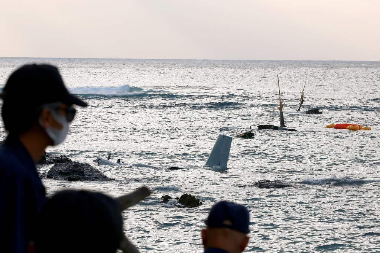 Japan's police forces stand before debris of an Osprey crash landed in the sea 13 December off the coast of Nago, Okinawa Island, Japan.