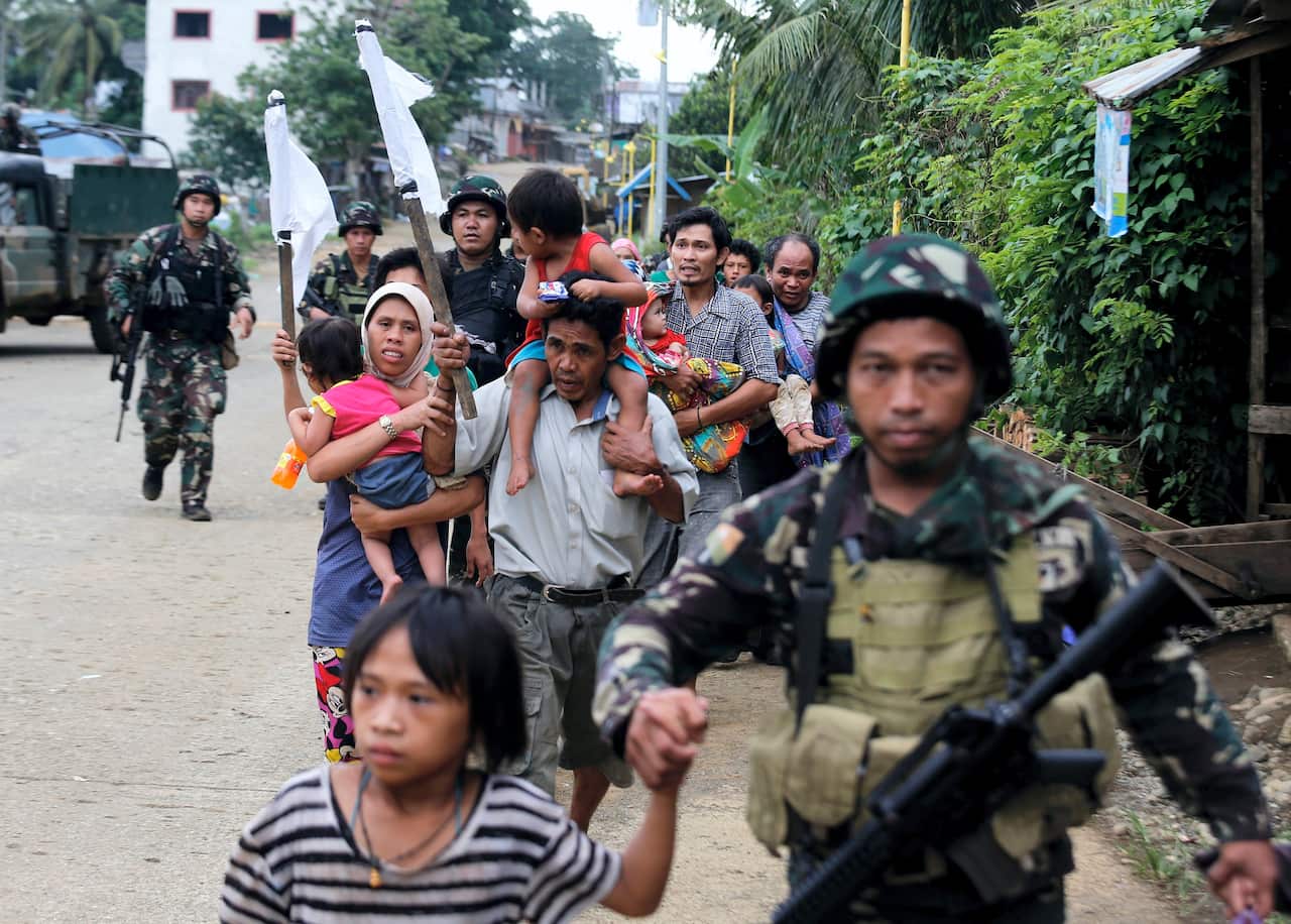 Trapped Filipino villagers are escorted by government troops during a rescue operation in Marawi city, Mindanao island, southern Philippines, 31 May 2017.