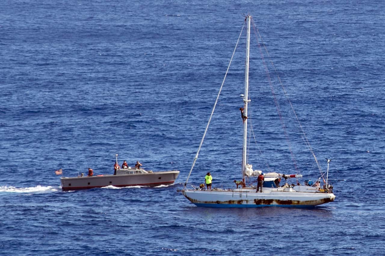 Sailors from the USS Ashland approach a boat with two Honolulu women and their dogs aboard as they were rescued after being lost at sea.