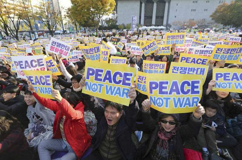 Anti-war protesters hold up their cards during a rally demanding peace of the Korean peninsula near U.S. Embassy in Seoul, South Korea, Sunday, Nov. 5, 2017. U.S.