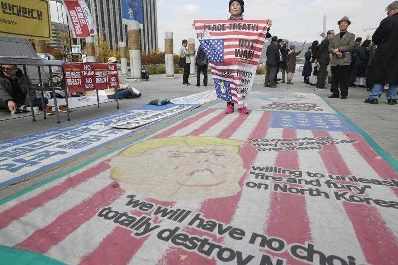 A South Korean protester stands on a cartoon depiction of US President Donald J. Trump during a rally held to show opposition to the US President's up coming visit.