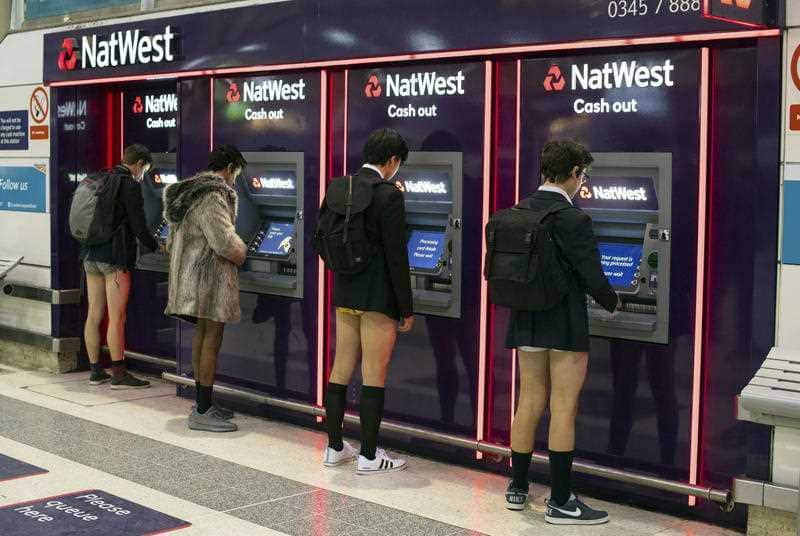 Men use cash machines at Liverpool Street station as they take part in No Trousers on the Tube day, in London, Sunday, January 7, 2018.