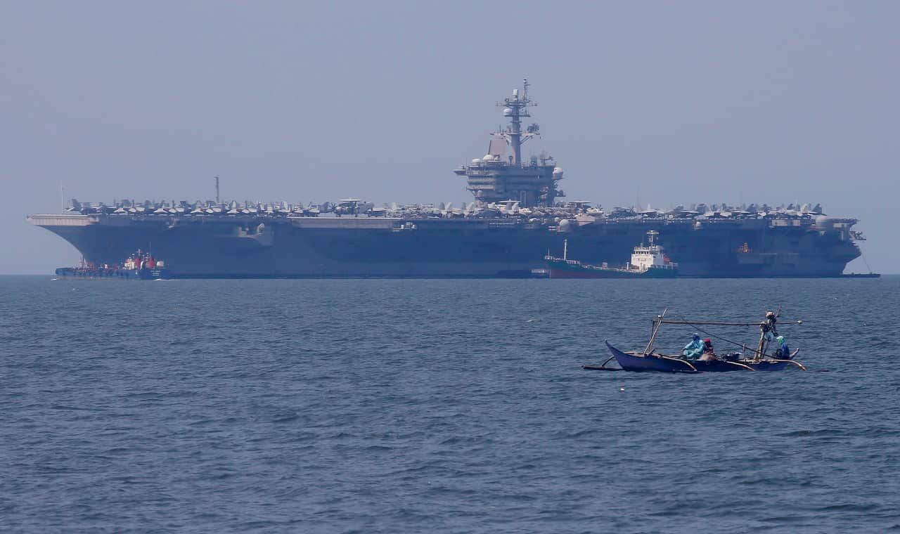 Fishermen on board a small boat pass by the USS Carl Vinson aircraft carrier at anchor off Manila, Philippines.