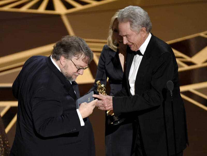 Guillermo del Toro inspects the envelope as Warren Beatty, right, presents him with the award for best picture for "The Shape of Water" at the Oscars.