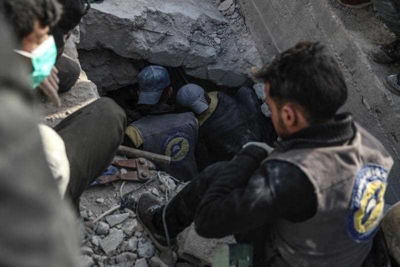 Civil defense rescuers search for a body of victim under a collapsed building that was targeted by a strike.