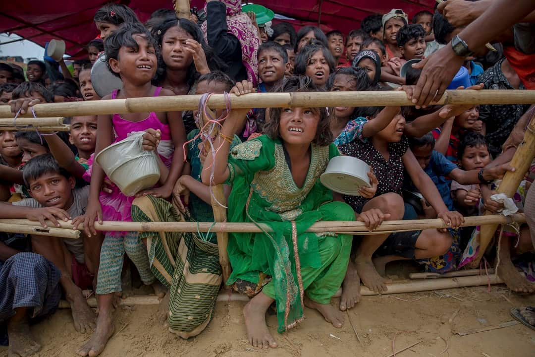 Rohingya children in Bangladesh wait for their turn to collect meals.