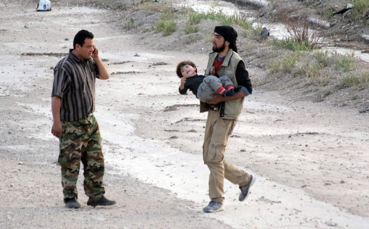 A man from the rebel-held Harasta City in the Eastern Ghouta in the countryside of Damascus, carries a child 