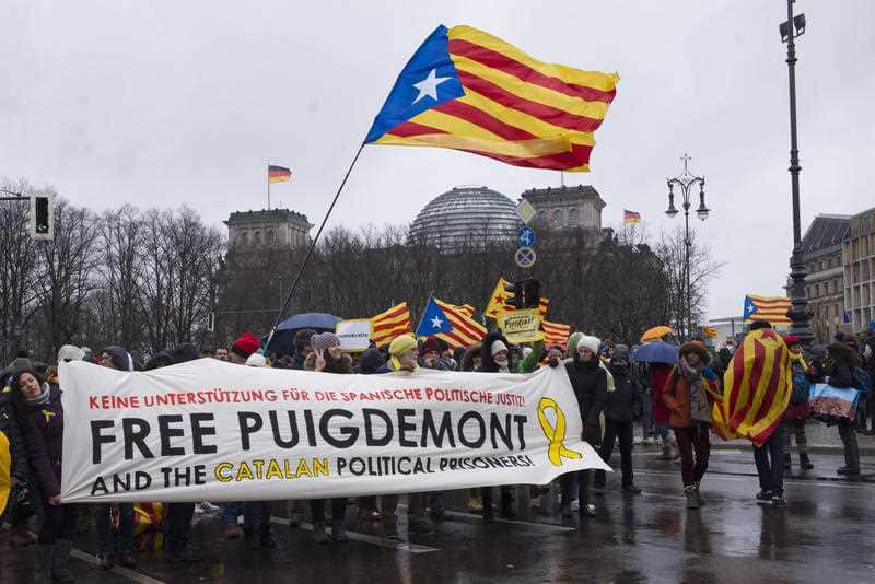 People with a banner lead a protest in front of the Reichstag building, condemning the arrest of Catalonia's former president, Carles Puigdemont in Germany, at a demonstration in Berlin, Germany, Sunday, April 1, 2018.