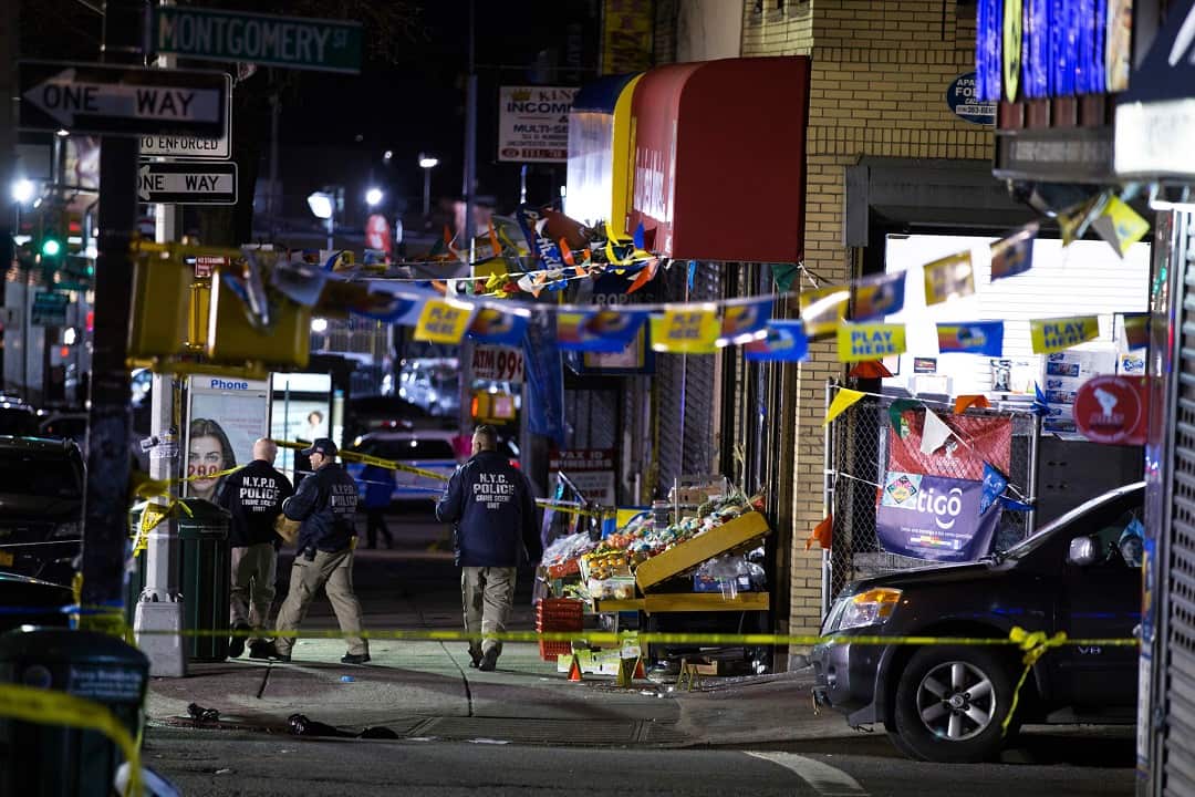 Investigators look over the scene where officers shot and killed a man in Brooklyn.