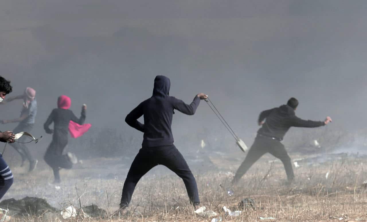 Palestinian protesters hurl stones at Israeli troops during clashes with Israeli troops along Gaza's border with Israel, Friday, April 13, 2018. 